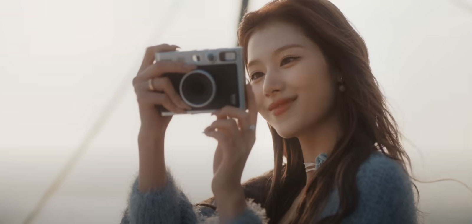 Twice Sana holding the Fujifilm Instax Mini EVO film camera in I Got You music video