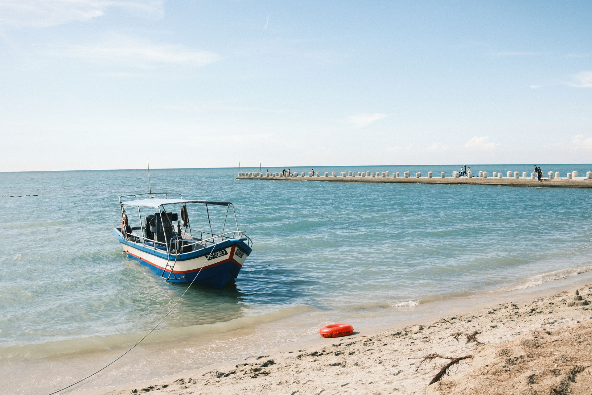 Yashica Gold 80s - Best Film Recipes For Summer - Jetty on the background with a boat at the beach with blueish sea