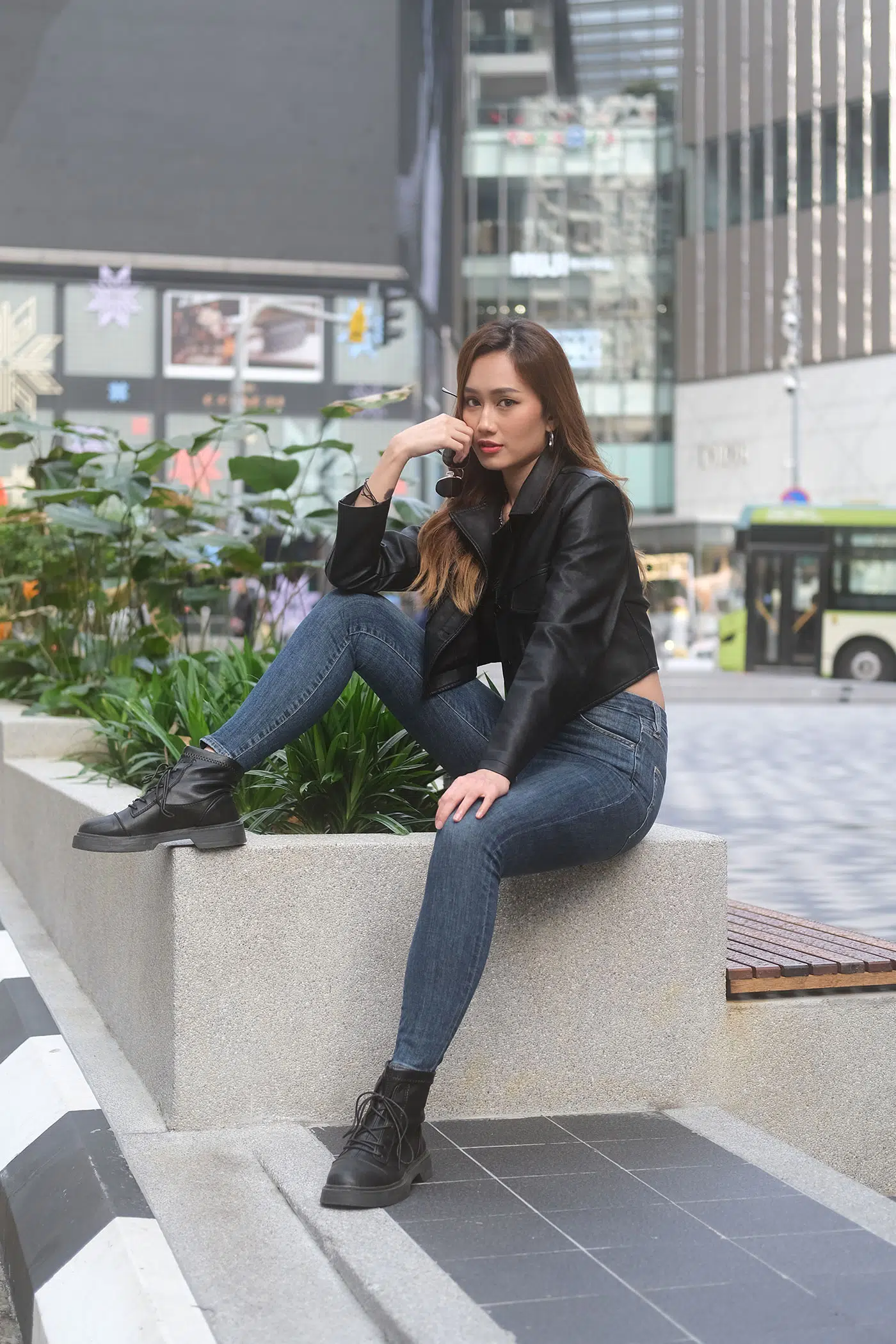 Casual sitting pose of a woman with one knee raised, elbow resting on it, hand near chin—relaxed yet strong posture for female portraits